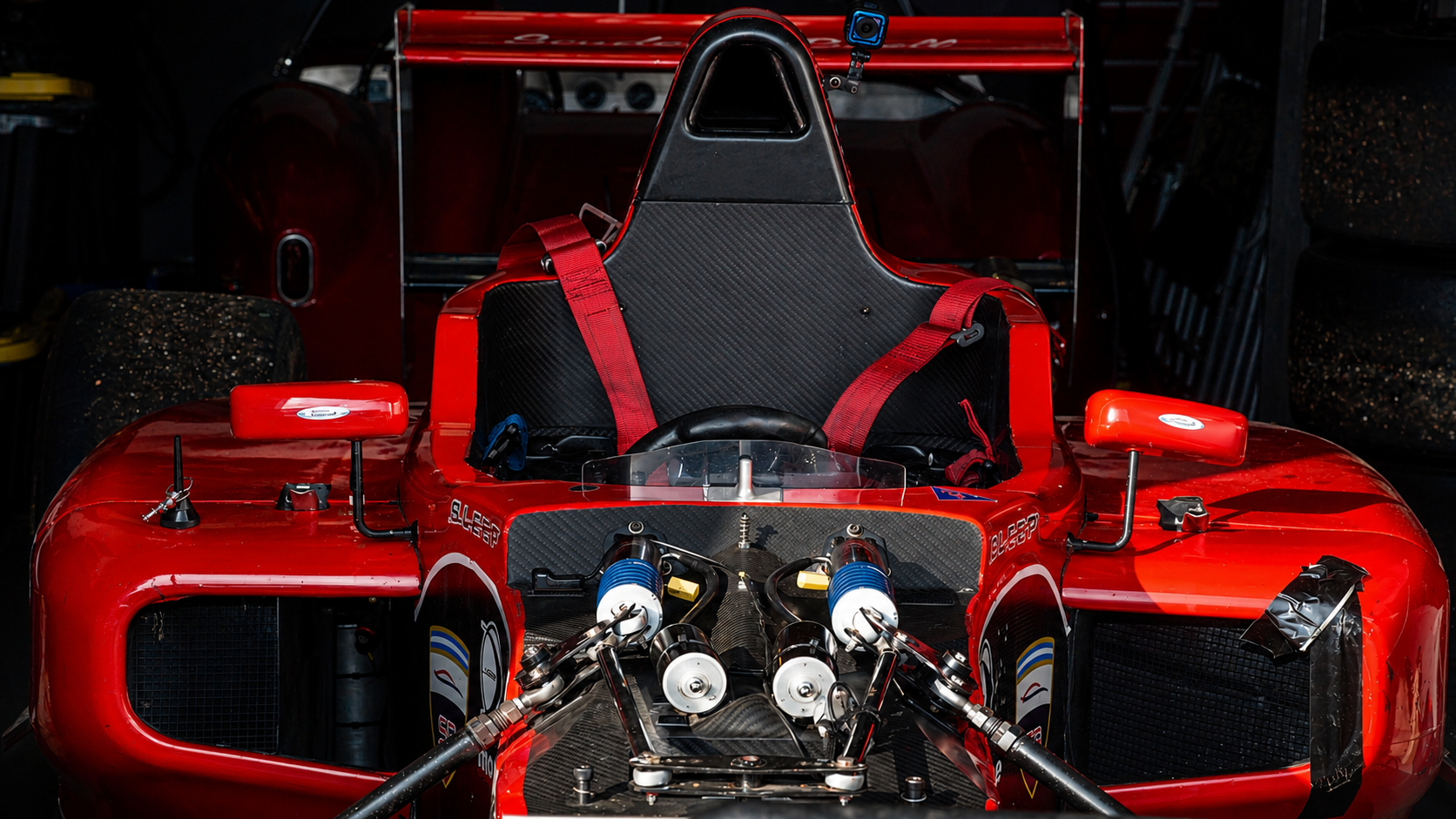 Red formula car front view in a garage preparation setting