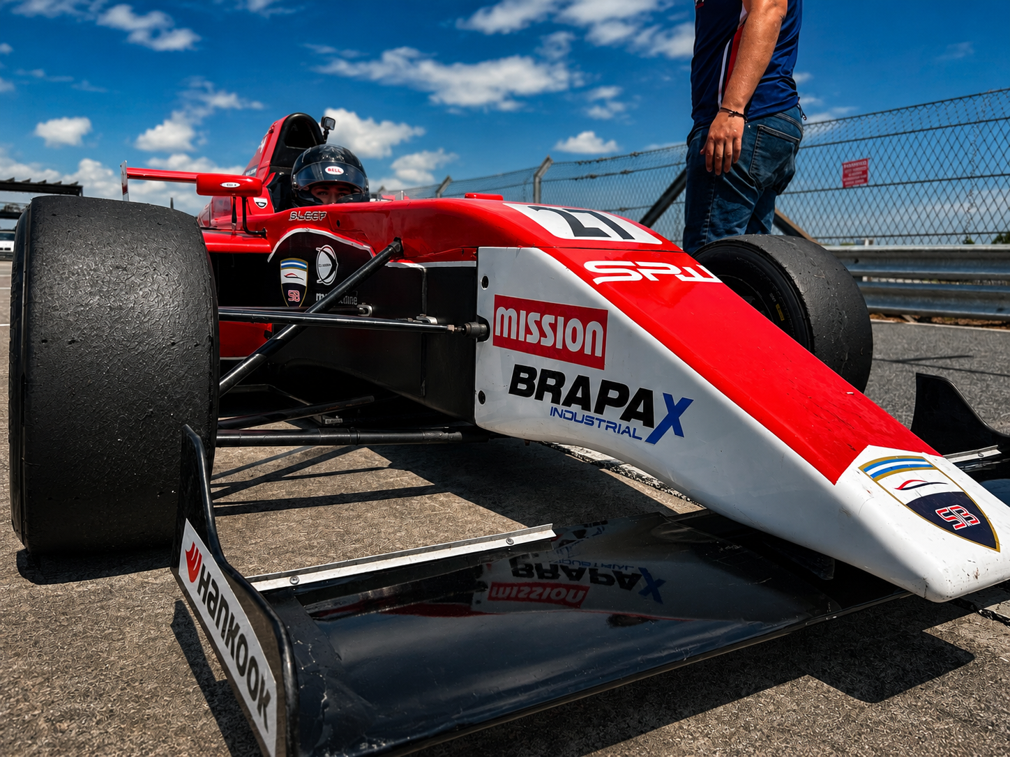 Red and white formula car in the pit lane from a low angle